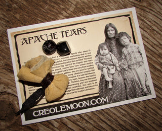 Apache Tears, two small round shiny stones on a card with an Apache mother and her children.