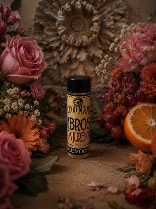 Bottle of Ambrosia oil surrounded by flowers and fruits on a rustic surface