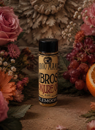 Bottle of 'Ambrosia Conjure Oil' by Ole Moon surrounded by flowers and fruits on a textured surface.