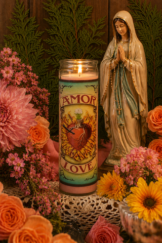 Candle with 'Amor' and 'Love' text, surrounded by flowers and a statue of a religious figure.
