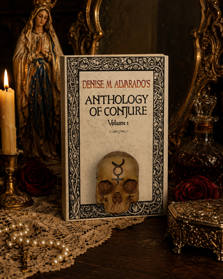 Book titled 'Anthology of Conjure' by Denise M. Alvarado on a table with decorative items.