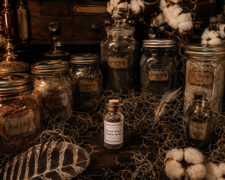 Vintage-style jars with labels on a textured surface with cotton and leaves.