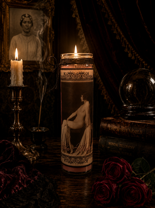Decorative candle with artistic design in a dark setting with candles and books.