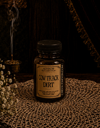 Bottle labeled 'Cow Track Dirt' on a textured surface with a dark background
