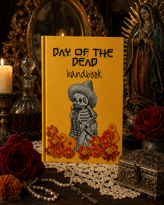 Book titled 'Day of the Dead Handbook' with a skeleton and flowers on a yellow background, surrounded by decorative items.
