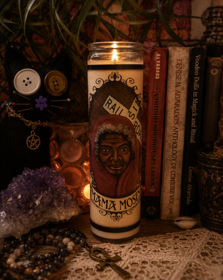 Candle with a portrait of Mama Moses and text on a mystical setting with books, crystals, and decor.