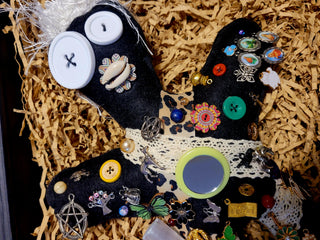 Decorative black ju ju doll with colorful buttons and embellishments on a textured surface