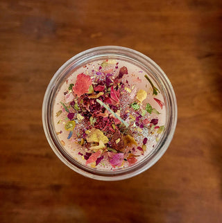 Top view of a jar candle with colorful dried flowers on a wooden surface
