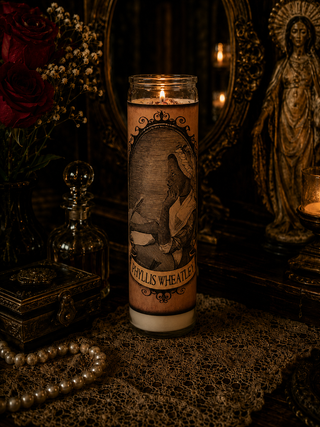 Candle with a printed design in a dark, mystical setting with a statue and flowers.