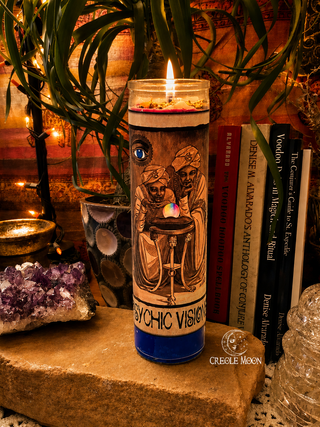 Candle with mystical design on a stone surface with books and crystals in the background