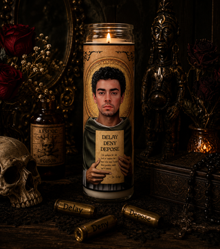Candle with a portrait and text in a dark, mystical setting with a skull and bottles.