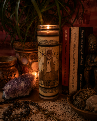 Conjure Doctor Candle with a printed design on a table with books, crystals, and other objects.