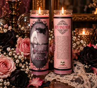 Two pink glass jar candles labeled 'Witching Hour' by Creole Moon, displayed on a table surrounded by black and pink roses, lace, and lit candles in a dark, gothic setting.