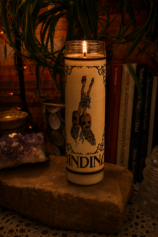 Candle with a graphic design on a stone surface with books and plants in the background