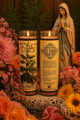Two candles with labels, a statue of a woman in prayer, and flowers on a textured surface.